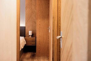 A narrow hallway with wooden walls and a door leading to a room.