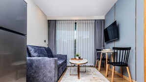 Un espacio habitable compacto con sofá, una mesa de comedor, sillas, televisor y refrigerador.