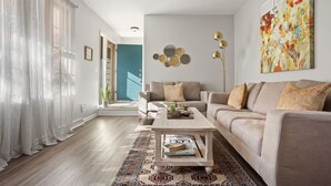 Un salon moderne avec un canapé, une table basse et un grand tableau abstrait.