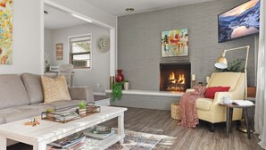 Un salon moderne avec une cheminée, un canapé, une table basse et un téléviseur.