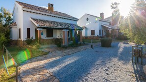 A white building with a tiled roof, a stone pathway, and a gravel driveway. - 2-bedroom Ibipozo Home With Pool (Pozo Alcon)