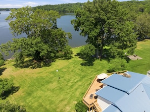 Une maison dotée d’une terrasse donnant sur un lac, entourée d’arbres.