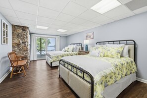 A bedroom with two beds, a stone accent wall, and a view through a glass door.