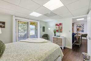 A bedroom with a bed, a desk, a chair, a window, and a door.