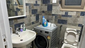A compact bathroom with a sink, washing machine, and toilet.