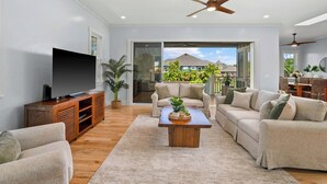 A spacious living room with a flat-screen TV, wooden entertainment unit, and a coffee table.