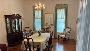 Comedor con mesa de madera, sillas, candelabro y un espejo grande.