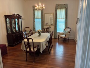 A dining room with a wooden table, chairs, a chandelier, and a large mirror.