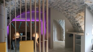 Une pièce aux murs de pierre, avec un lit, un bureau et une chaise.