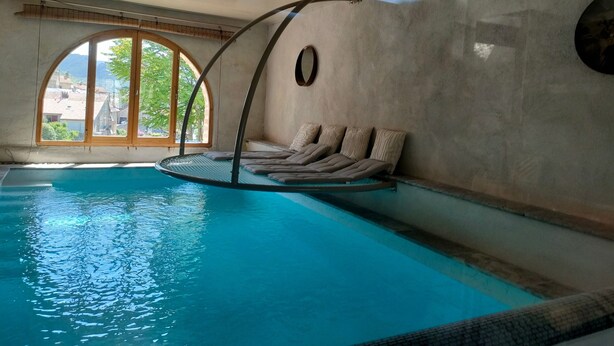 Une piscine intérieure avec un coin détente et une vue sur l’extérieur.