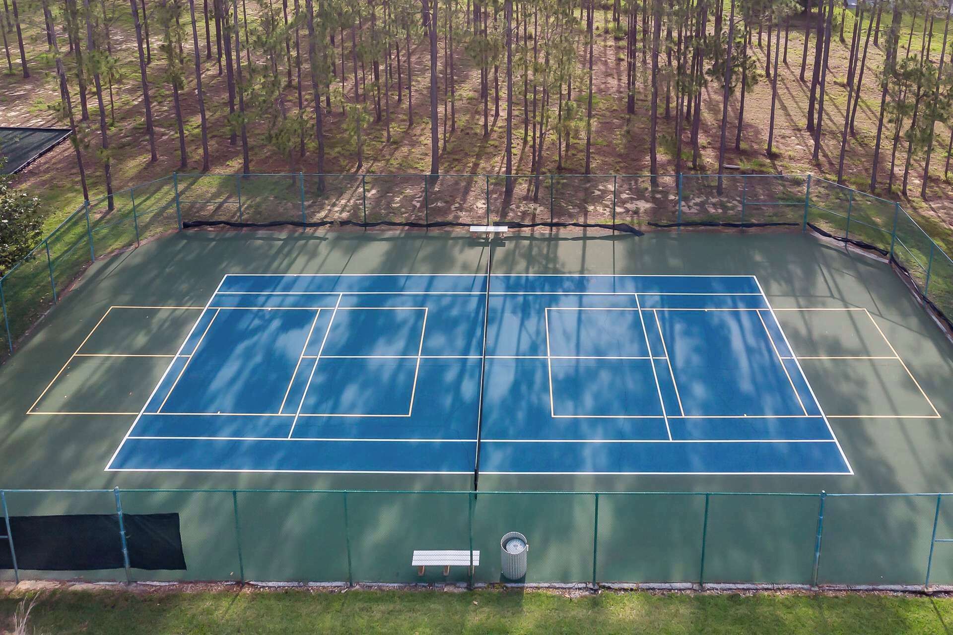 Un court de tennis en plein air, entouré d’arbres.
