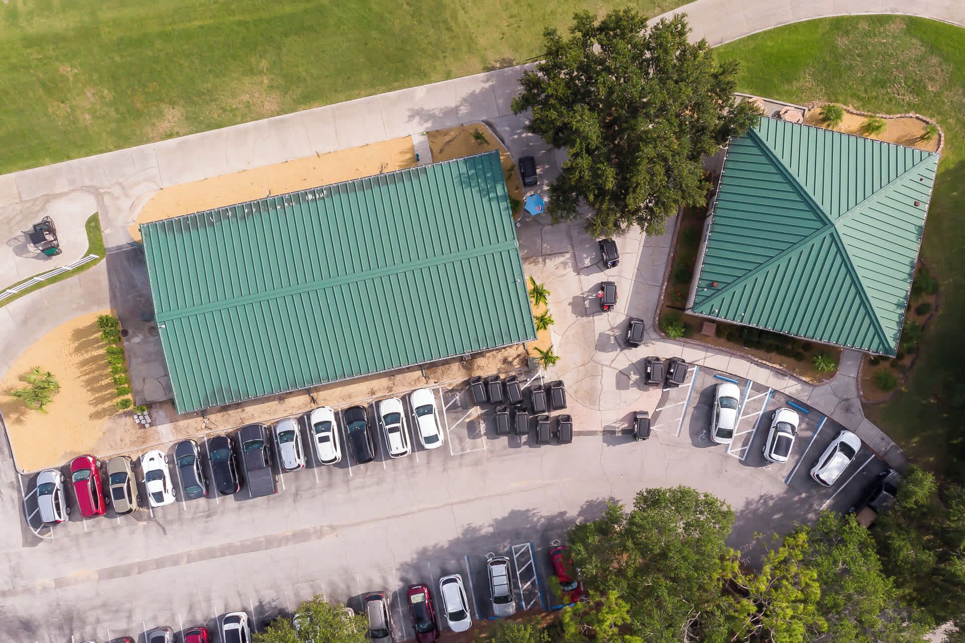 An aerial view of a parking lot with several cars and a building with a green roof.