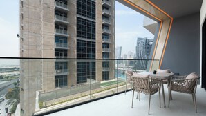 Ein Balkon mit Tisch und Stühlen, mit Blick auf eine Stadtlandschaft und eine Straße.