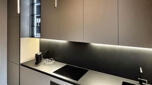 A modern kitchen with a sleek black countertop, a built-in wine rack, and pendant lighting. - Modern three-room apartment in Via Lambrate, 13 - Mirable PM (Milano)
