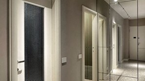 A hallway with a mirrored wall, a door with a textured glass panel, and a light switch on the wall. - Modern three-room apartment in Via Lambrate, 13 - Mirable PM (Milano)