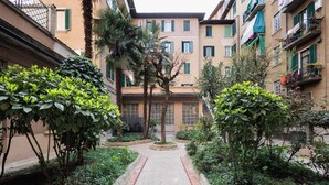 A courtyard with a central pathway flanked by greenery and buildings with balconies. - Modern three-room apartment in Via Lambrate, 13 - Mirable PM (Milano)
