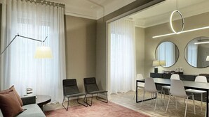 A modern hotel room with a grey sofa, two armchairs, a dining table with chairs, a large mirror, and a ring light. - Modern three-room apartment in Via Lambrate, 13 - Mirable PM (Milano)
