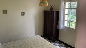 Een kamer met een bed, een kastje, een hanglamp en een raam met gordijnen.