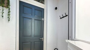 A dark blue door with a white frame, a small metal rack, and a white wall with a 'ROJO Stays' logo.