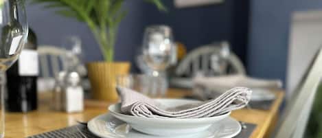 A dining table with a folded napkin, a wine bottle, and a potted plant.