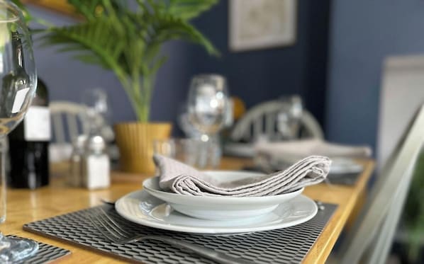 A dining table with a folded napkin, a wine bottle, and a potted plant.