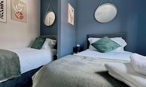A hotel room with two beds, a round mirror, and artwork on the walls.