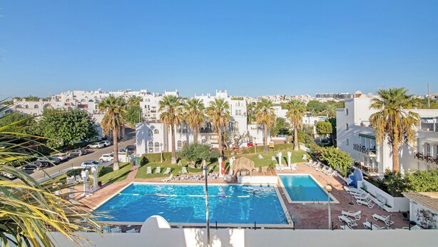Ett hotell med en swimmingpool, palmer och utsikt över staden.