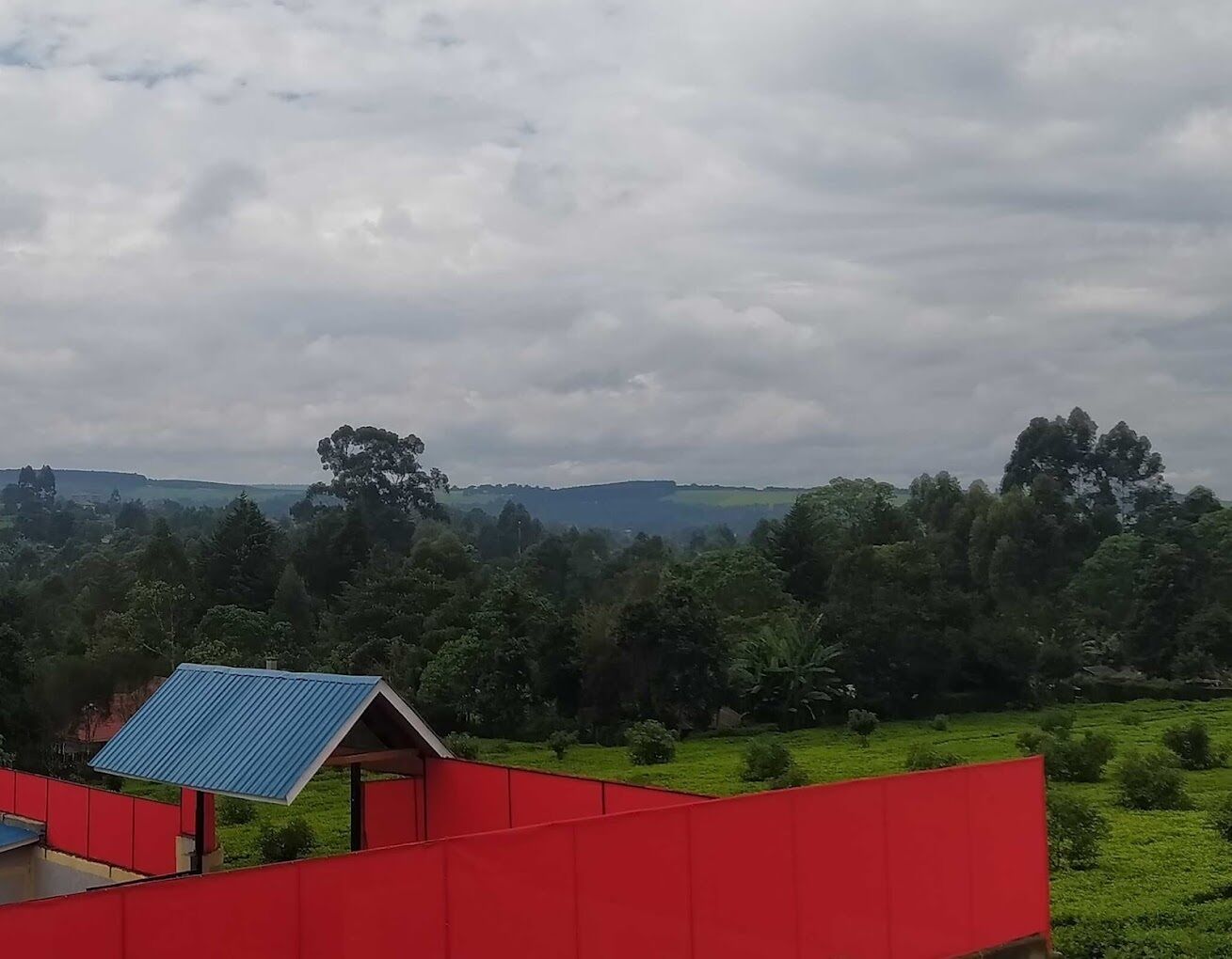 A rural landscape with a red building and a small blue-roofed structure.