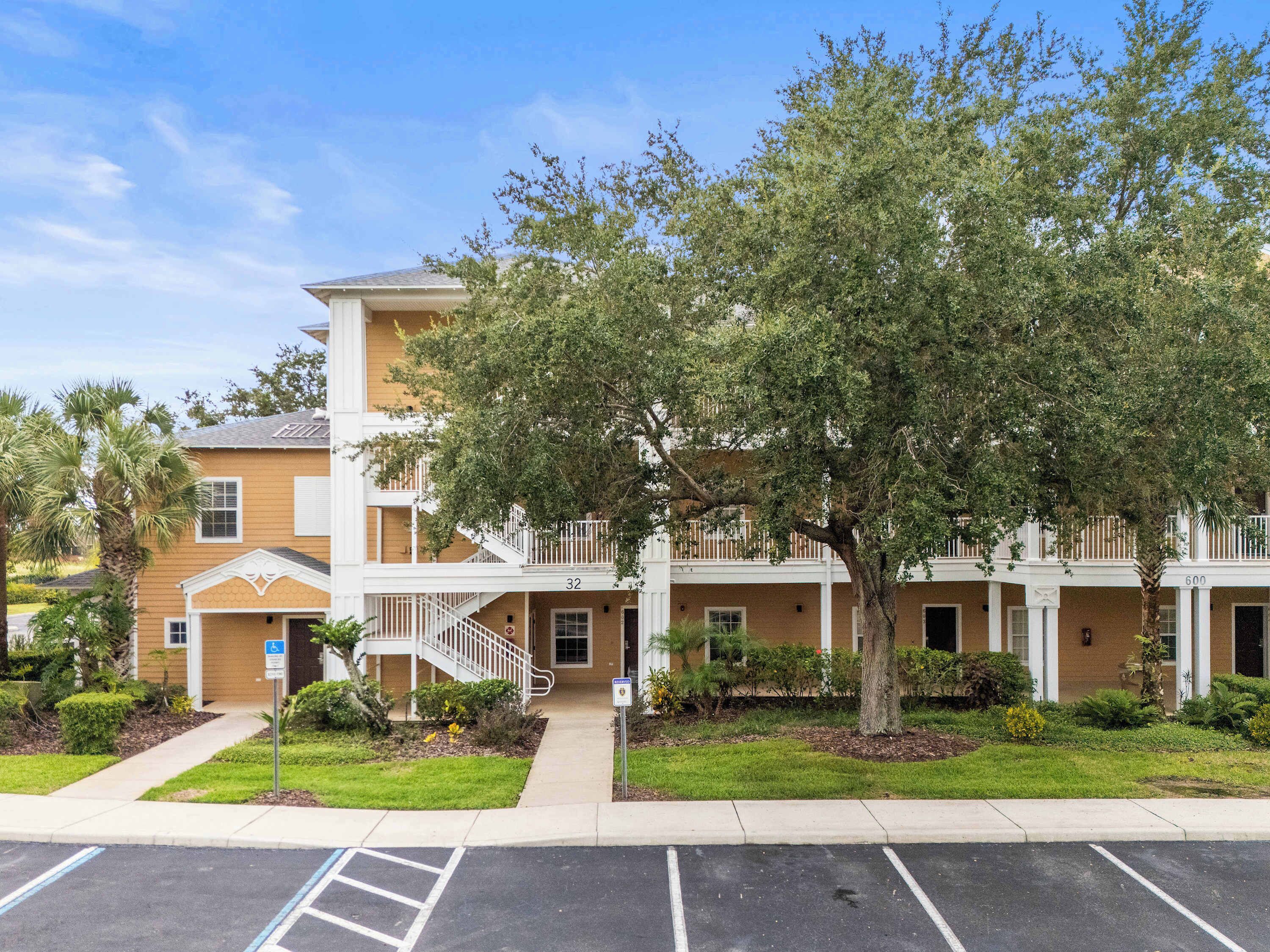 Ein mehrgeschossiges Gebäude mit einer zentralen Treppe, nummerierten Wohnungen und einem Parkplatz.