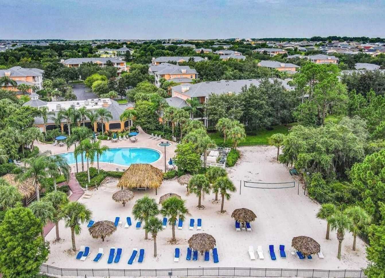 Ein Resort mit Swimmingpool, Liegestühlen und Palmen.