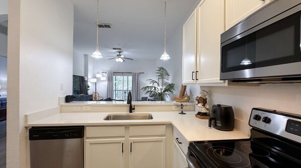 A modern kitchen with a dishwasher, stove, microwave, and a ceiling fan. - Palm Breeze At Bahama Bay 8ppl (Davenport)