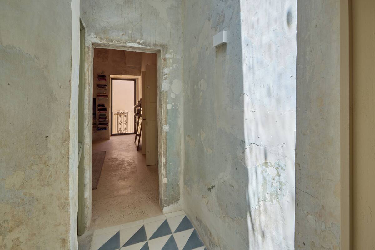 A narrow hallway with peeling walls and a tiled floor.