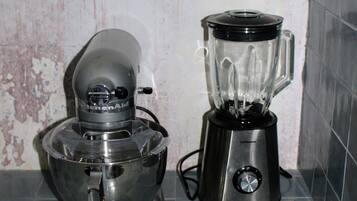 A kitchen with a blender and a food processor on a tiled floor.