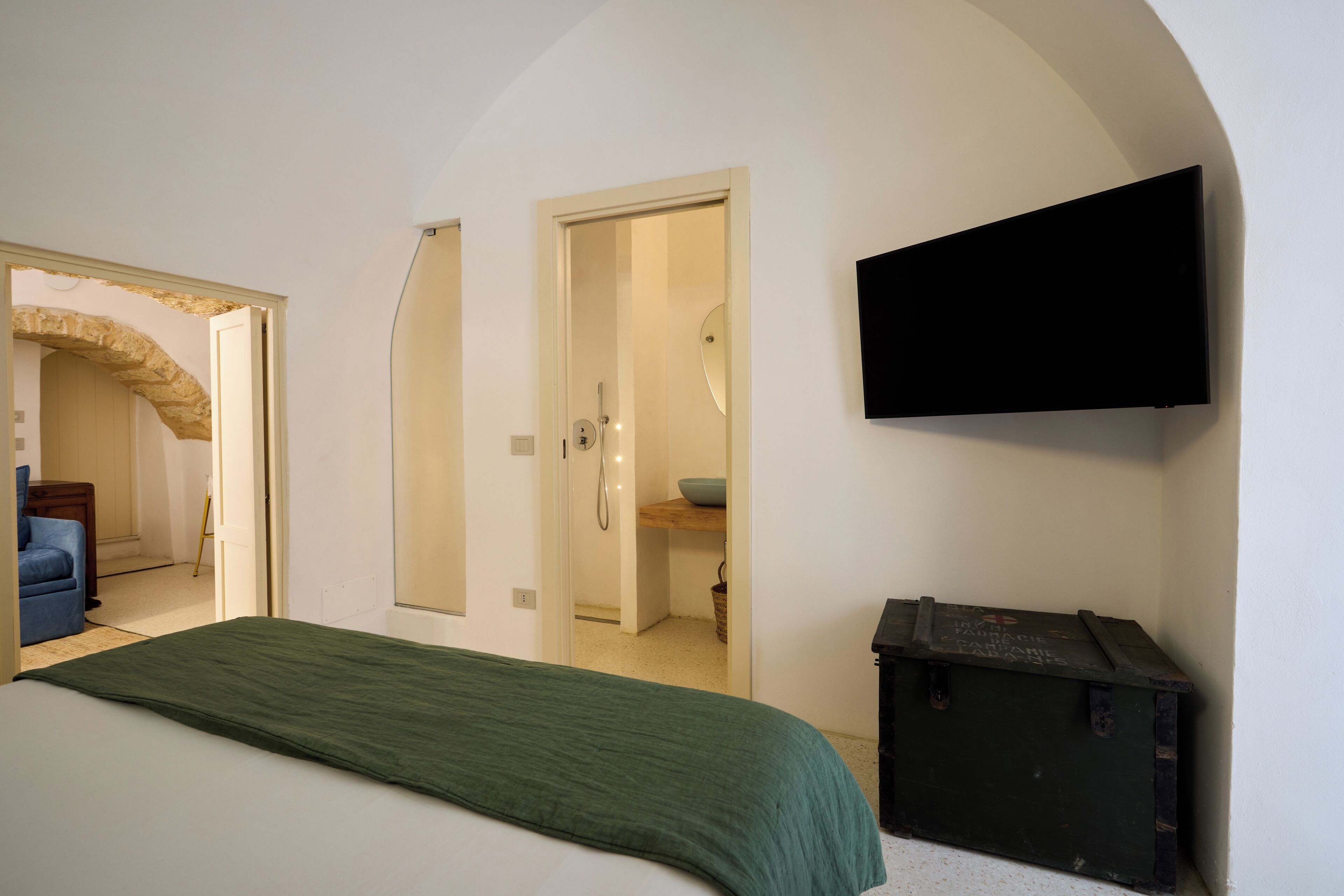 A bedroom with a bed, a television mounted on the wall, and a small storage unit.