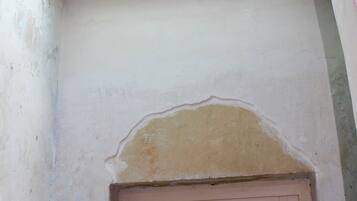 A room with a skylight, a door, and a wall with peeling paint.