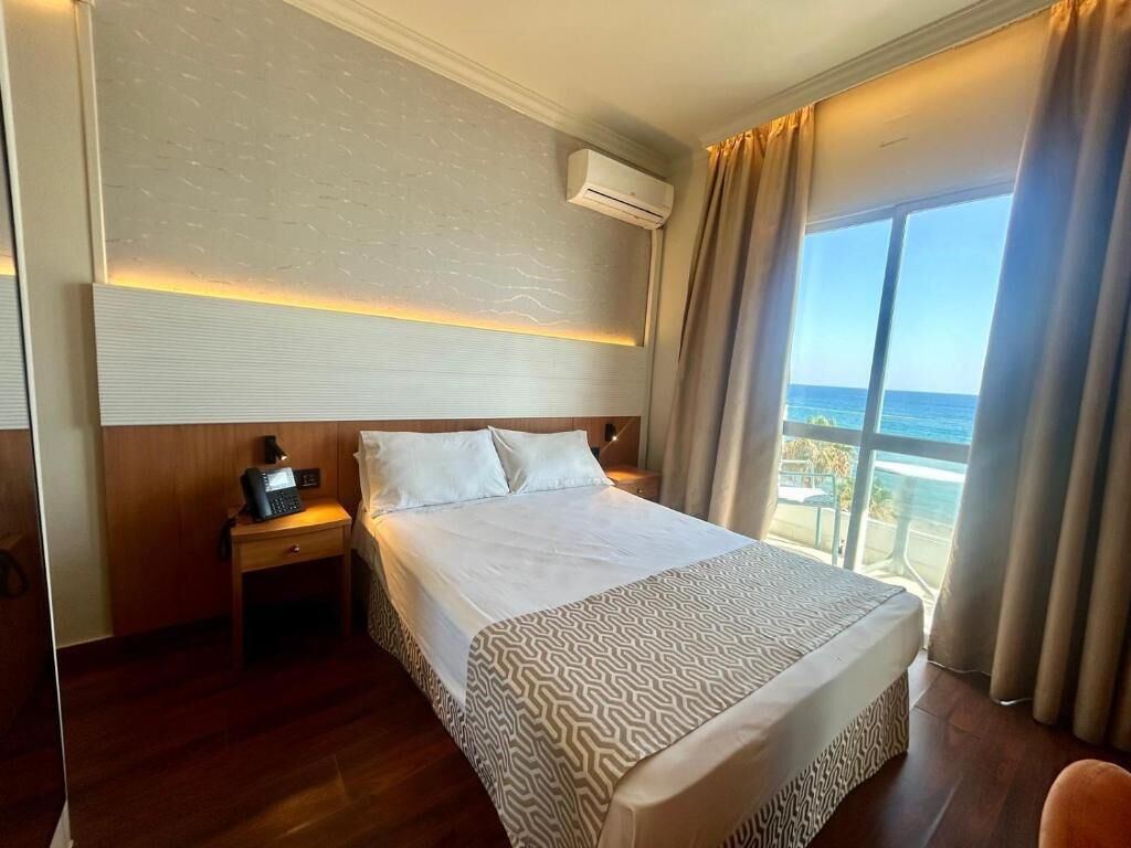 Ein Hotelzimmer mit einem großen Bett, einem Nachttisch, einer Klimaanlage und Blick auf den Ozean.
