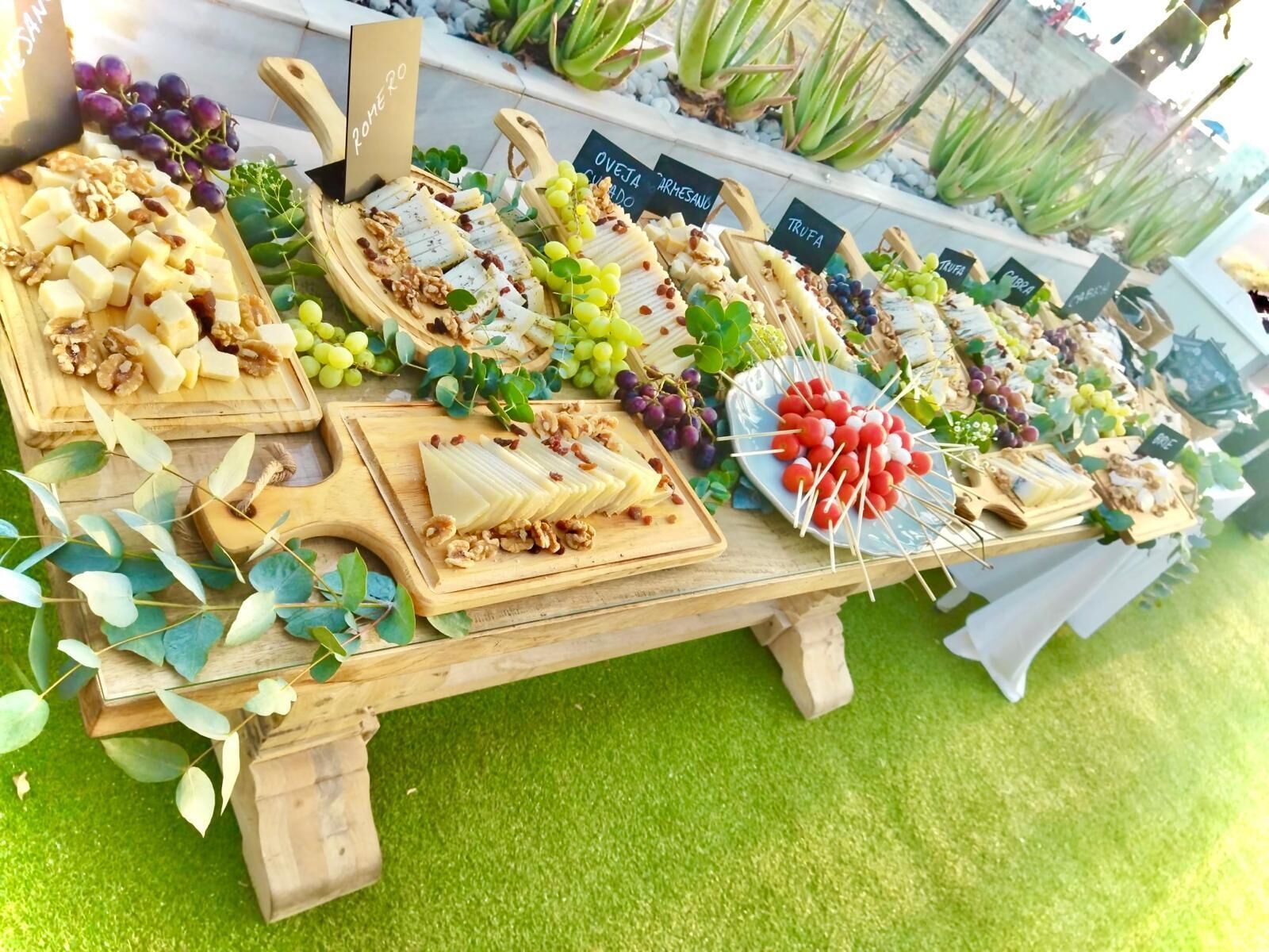 Une présentation de fromages et de fruits, avec différents types de fromages et des raisins, disposés sur des planches en bois.