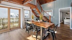 A spacious dining area with a wooden table and chairs, a staircase, and a view of the outside. - Captains Quarters Cottage, Ocean City MD (Ocean City)