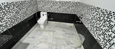 Ein Badezimmer mit Toilette, Dusche und Fliesenboden.