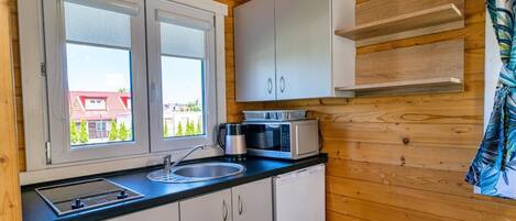 A compact kitchen with a sink, cabinets, and a microwave.
