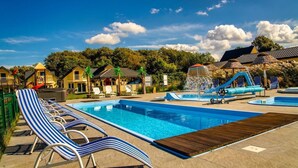 A swimming pool area with lounge chairs, a water slide, and a small water fountain. - Comfortable Holiday Homes With a Pool (Ustronie Morskie)