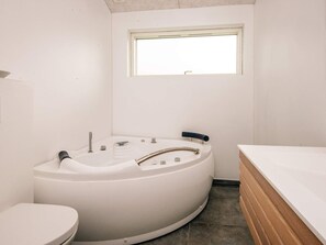 A bathroom with a white bathtub, a toilet, and a window. - 4 Star Holiday Home in Hemmet (Hemmet)