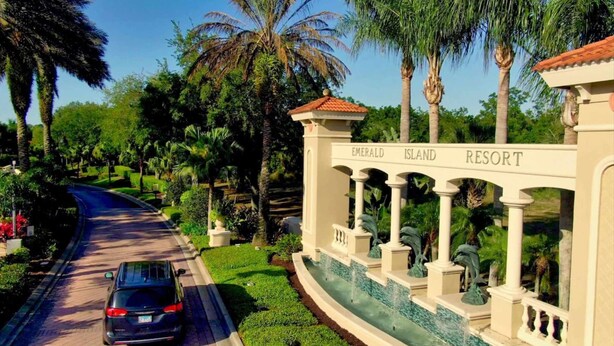 A road leading to Emerald Island Resort with a car parked on the side. - Magic Getaway at Emerald Island (Kissimmee)