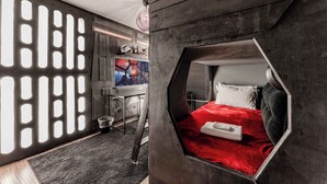 A room with a hexagonal window bed, a desk with a computer, and a wall with a geometric light fixture. - Magic Getaway at Emerald Island (Kissimmee)