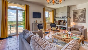 Ein großzügiger Wohnbereich mit Sofa, Sesseln, Couchtisch und Fernseher.