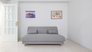 A modern room with a grey sofa, a white door, and two framed artworks on the wall.