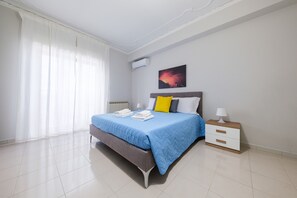 Een slaapkamer met een bed, een nachtkastje, een radiator en een raam met gordijnen.