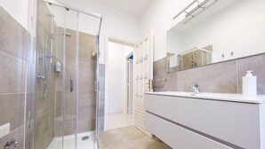 A modern bathroom with a glass shower enclosure, a white vanity with a mirror, and beige tiled walls. - Room 'Stromboli' with Sea View, Wi-Fi and Air Conditioning (Pace del Mela)