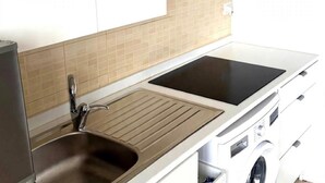A modern kitchen with a sink, stove, and built-in washing machine. - Room 'Stromboli' with Sea View, Wi-Fi and Air Conditioning (Pace del Mela)