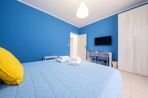 Une chambre avec un lit, une chaise, une télévision et une armoire.